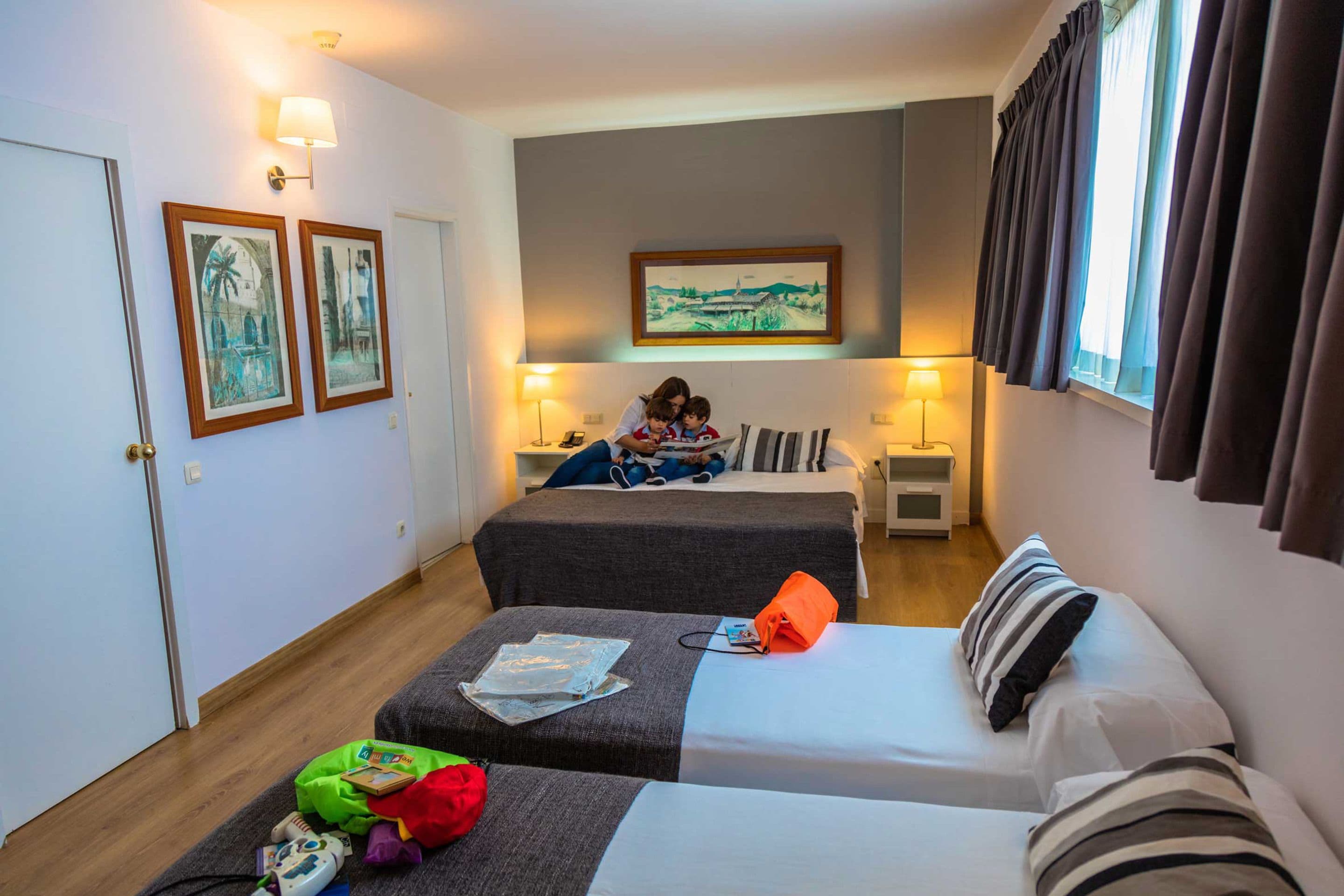 A hotel room with two beds, a sofa, a small table, and a painting on the wall.