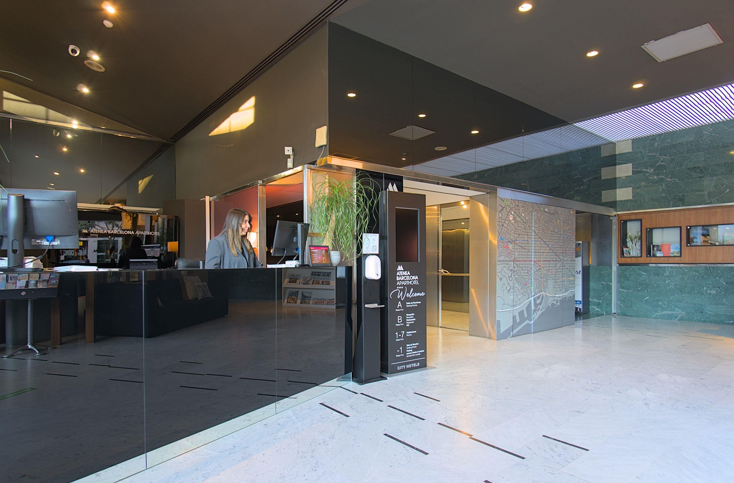 A modern hotel lobby with a reception desk, a digital directory, and a map on the wall.