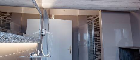A modern bathroom with a wooden ceiling, a large mirror, two sinks, and a glass shower enclosure.