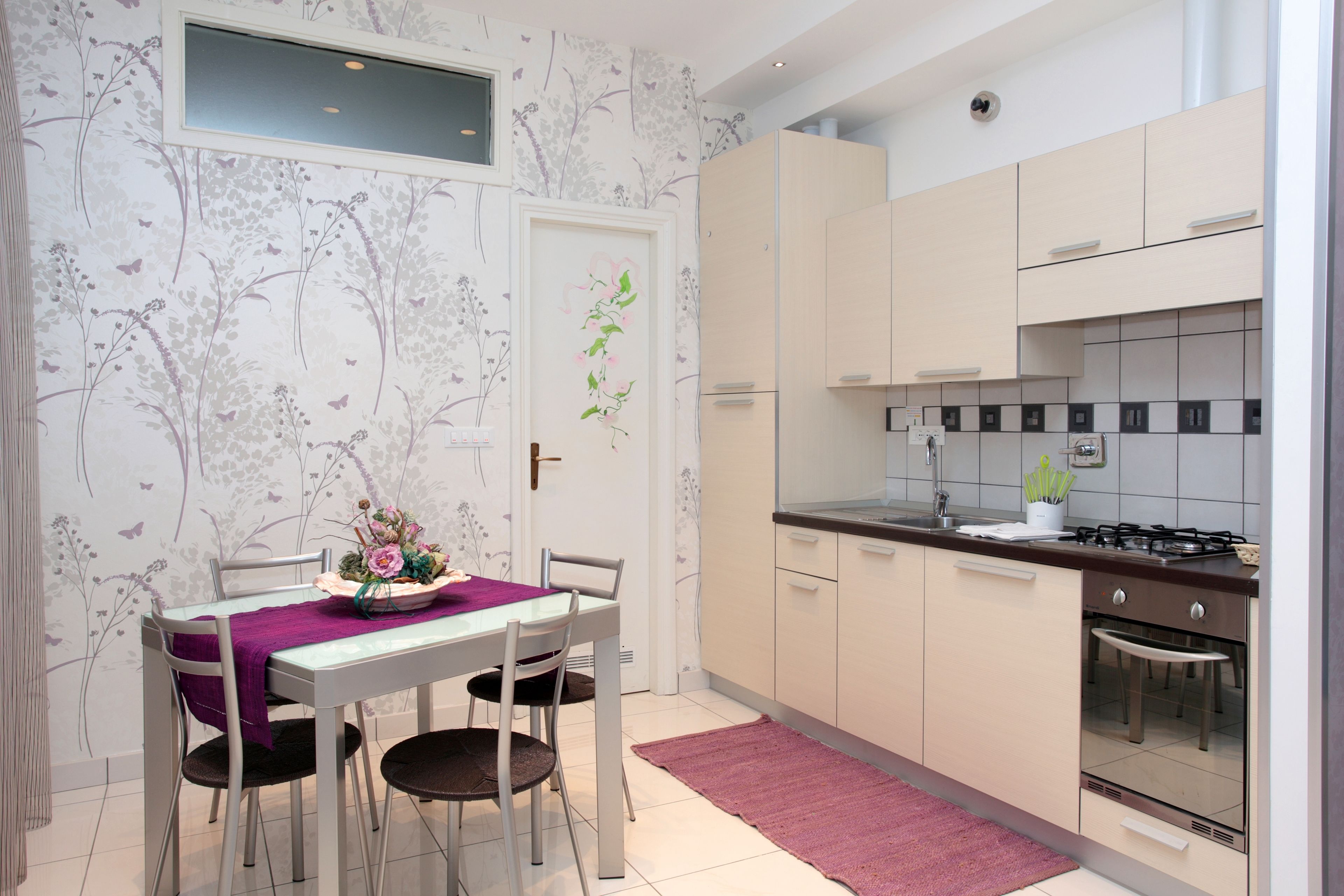 Una cocina moderna con armarios blancos, una estufa a gas y un comedor con mesa y sillas.