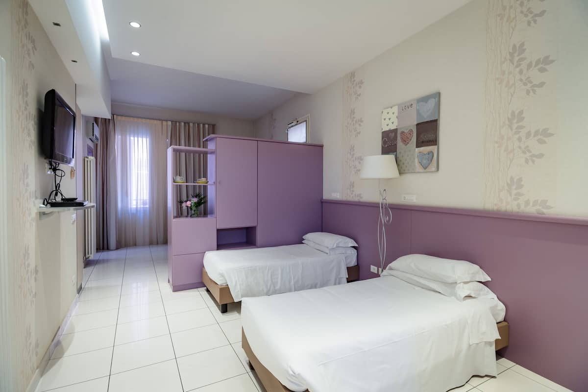 Una camera d'albergo con due letti, televisione, scrivania e bagno.