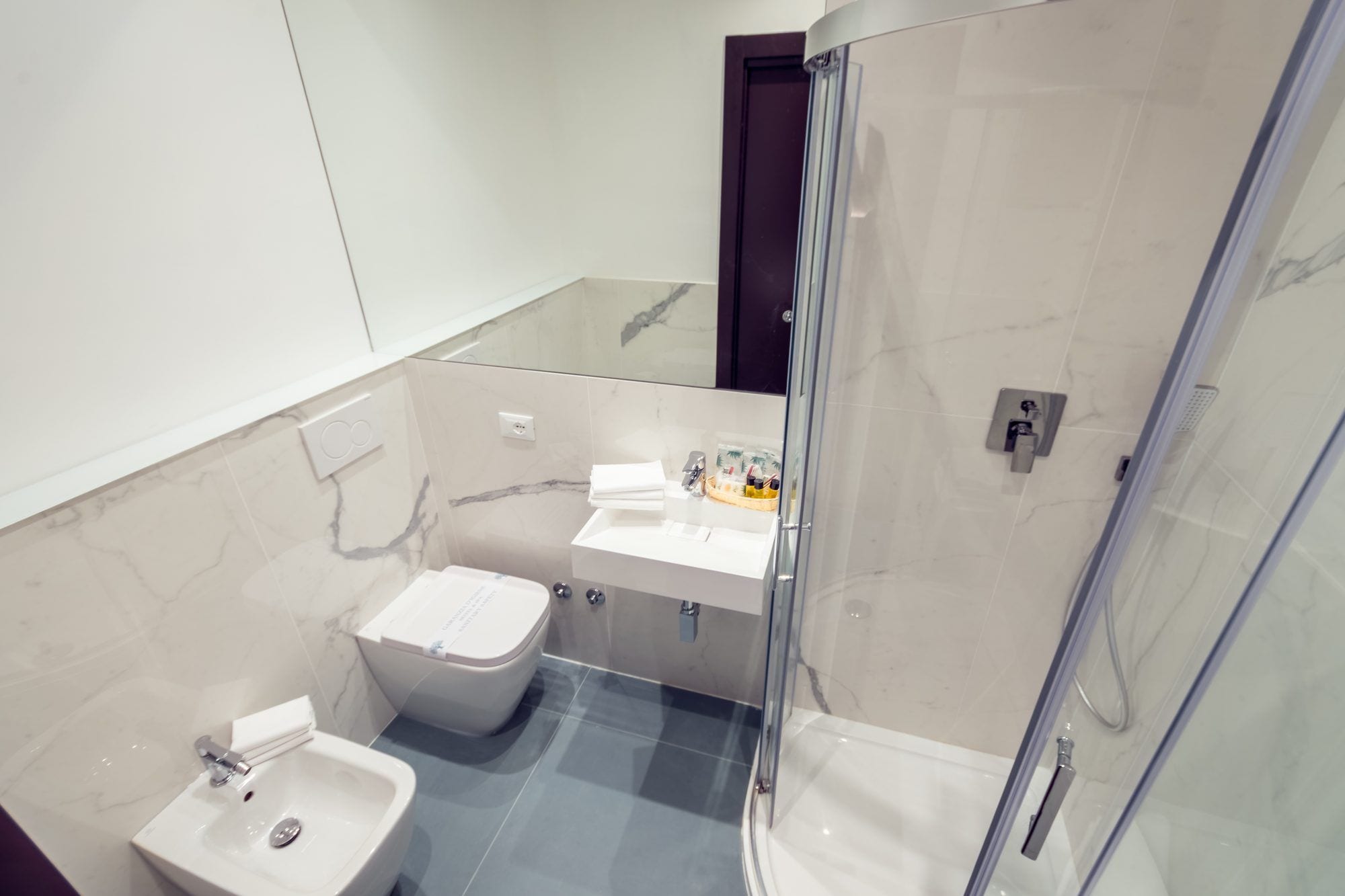 Et moderne badeværelse med en brusekabine i glas, en hvid vask og et toilet.