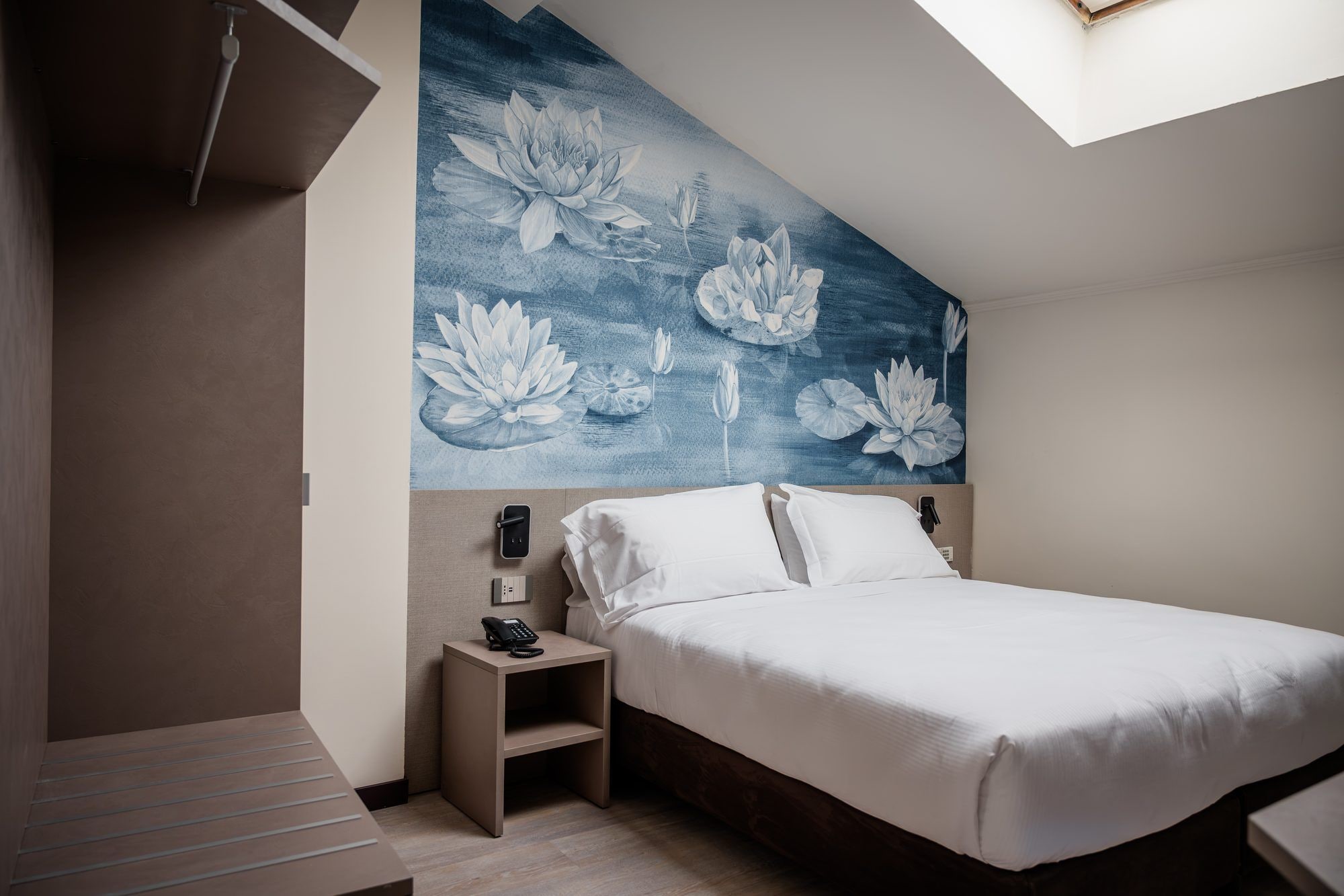 A bedroom with a bed, a nightstand with a phone, and a wall with a floral mural.