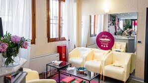 A hotel room with a sofa, armchairs, a glass coffee table, a mirror, and a vase with flowers. - Hotel Centrale (Bologna)