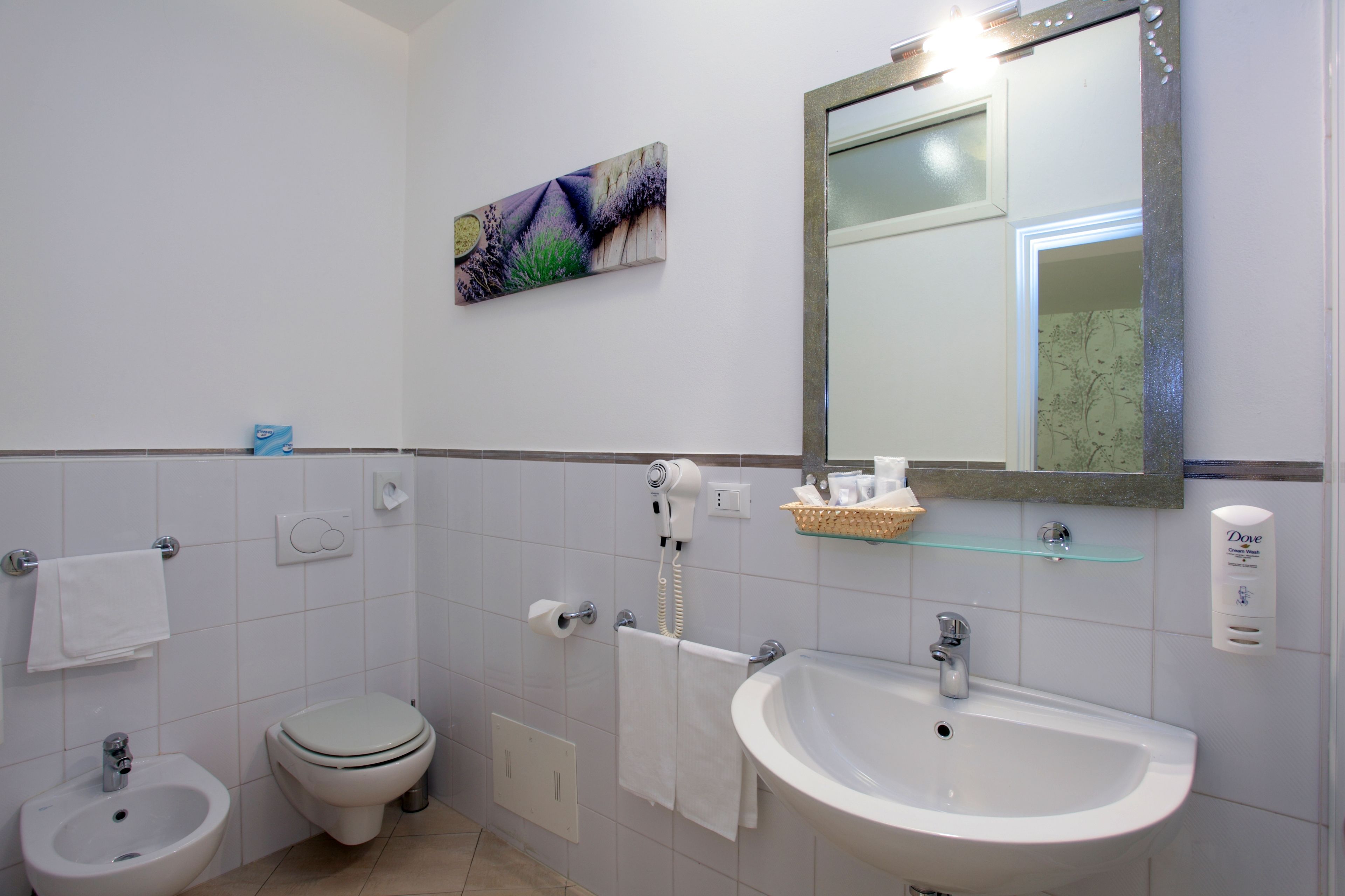 Un baño con bidé, inodoro, lavabo y espejo.