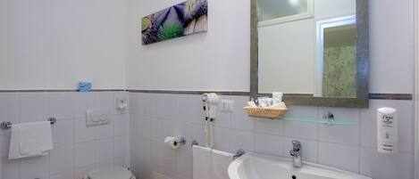 Un baño con bidé, inodoro, lavabo y espejo.