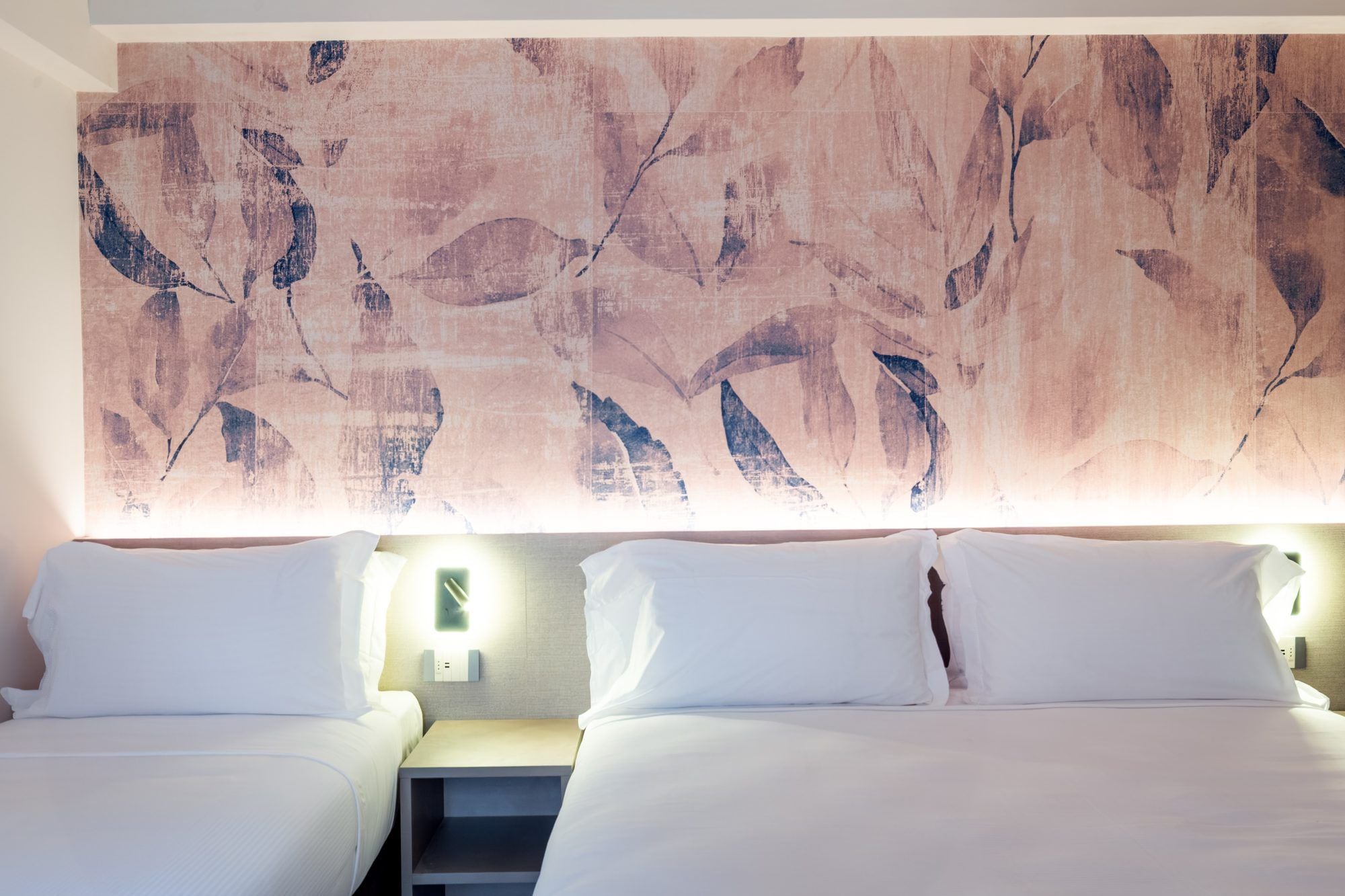 Ein Hotelzimmer mit zwei Betten, einem großen abstrakten Gemälde an der Wand und Nachttischlampen.