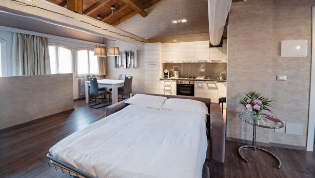 A modern bedroom with a large bed, a desk, and a kitchenette. - Hotel Centrale (Bologna)