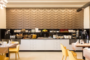 A modern kitchen area with a central island, equipped with various appliances and utensils, and a patterned wall behind the counter.