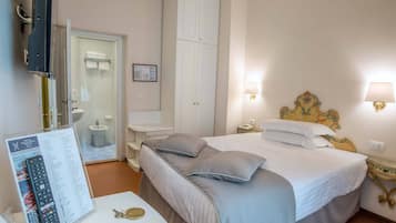 Une chambre d’hôtel avec un lit, des lampes de chevet, une télévision et une salle de bain visible à travers une porte ouverte.