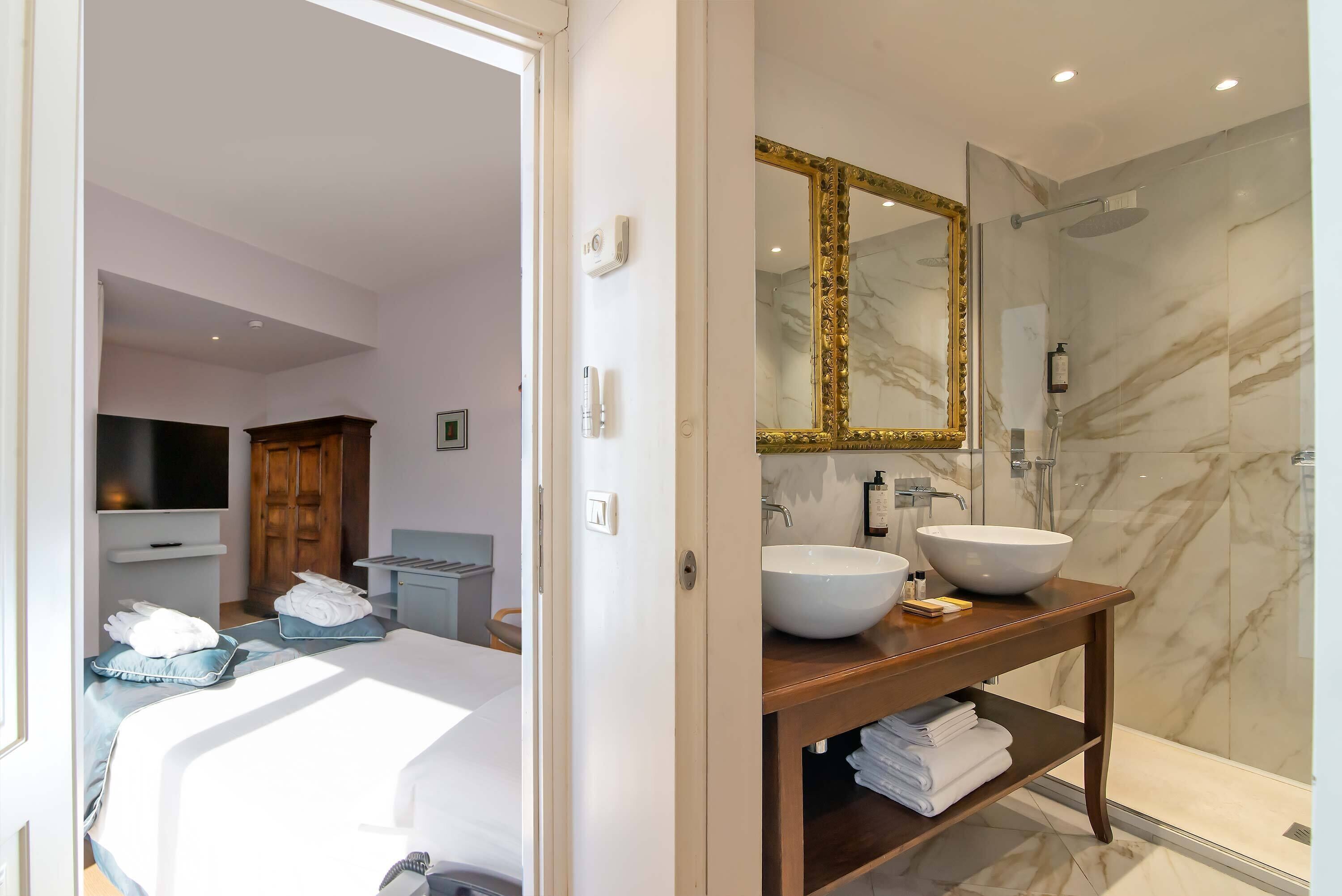 Un bagno moderno con uno specchio grande, una parete doccia in marmo e un mobile lavabo in legno con lavandino bianco.
