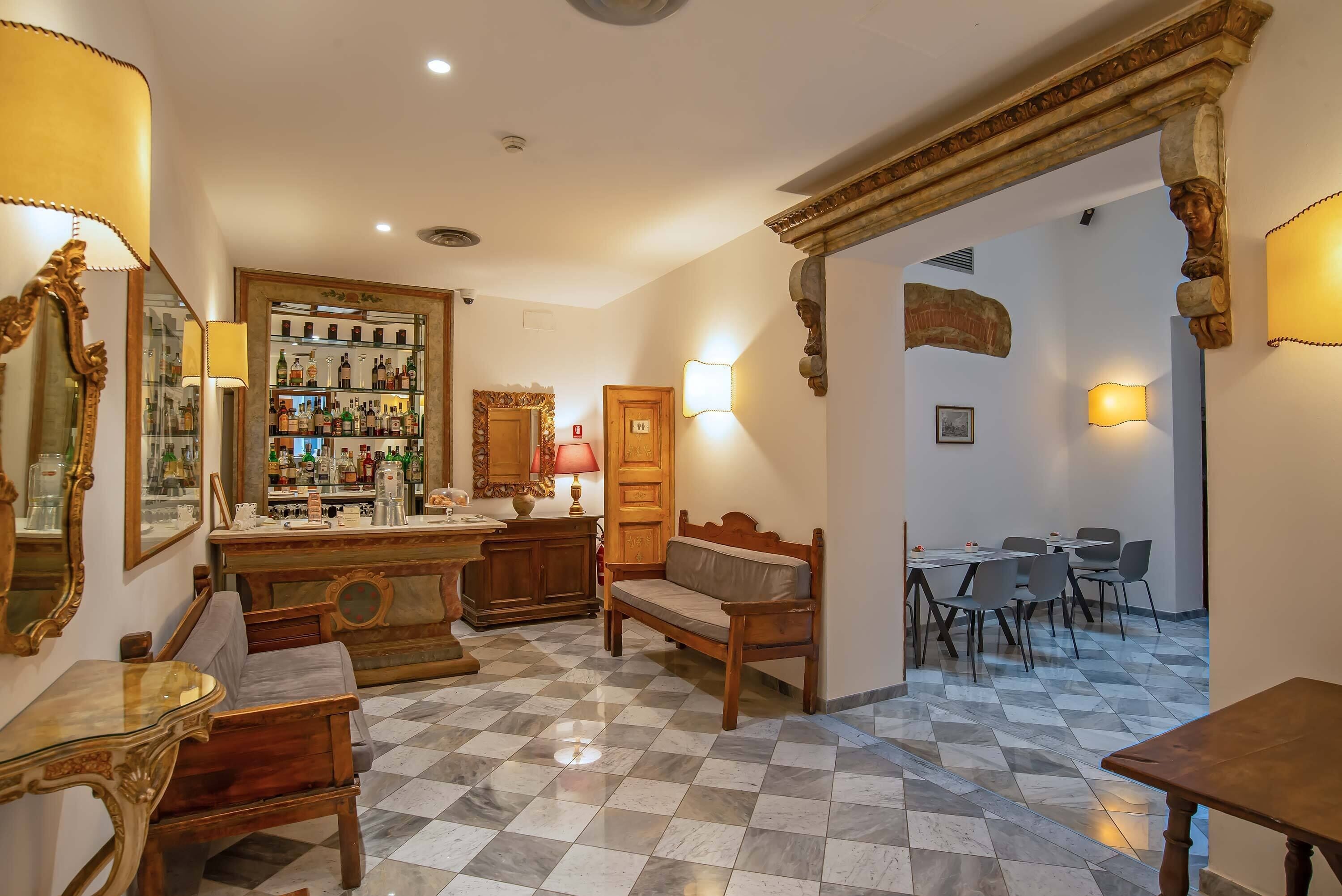A bar area with a checkered floor, wooden furniture, and a bar stocked with bottles.