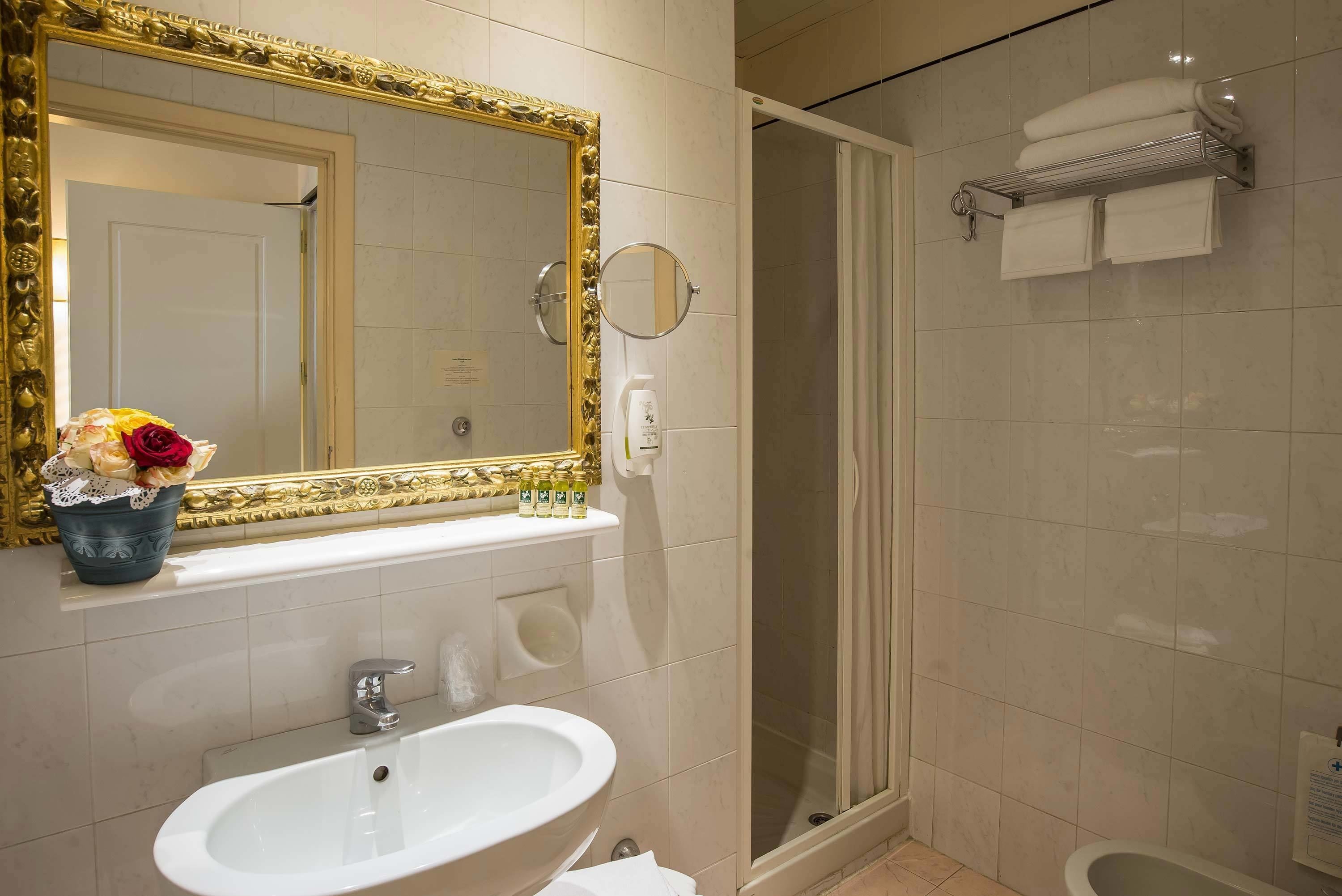Ein Badezimmer mit großem Spiegel, Waschbecken, Dusche und Handtuchhalter.