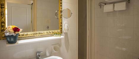 Ein Badezimmer mit großem Spiegel, Waschbecken, Dusche und Handtuchhalter.