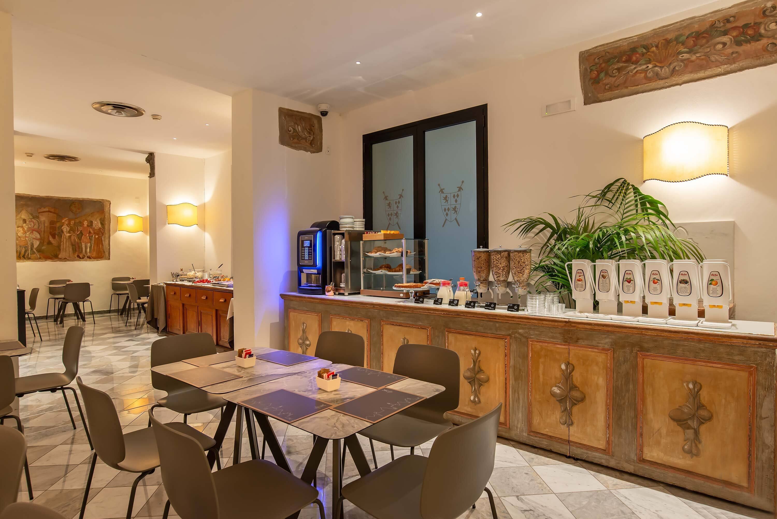 A restaurant with a marble floor, a counter with food items, and a large plant.