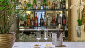 Una zona de bar con una planta en maceta, dos vasos de agua, una botella de champán y un cubo de hielo.