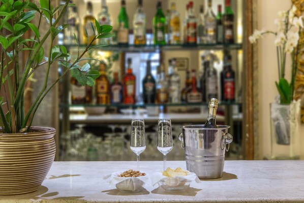 Una zona de bar con una planta en maceta, dos vasos de agua, una botella de champán y un cubo de hielo.