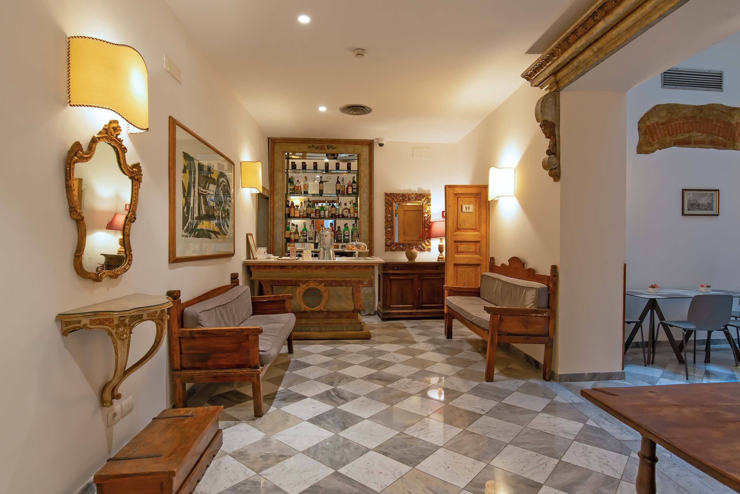A hotel room with a checkered floor, wooden furniture, a bar area, and a dining area.
