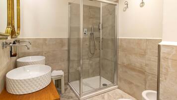 A modern bathroom with a glass-enclosed shower, two round sinks, and a toilet.