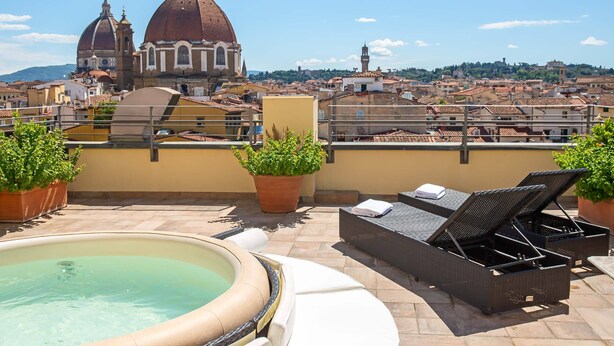 Una terraza en la azotea con una bañera de hidromasaje, sillones de descanso y plantas en macetas.
