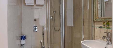 A modern bathroom with a glass-enclosed shower, a white sink, and a toilet.