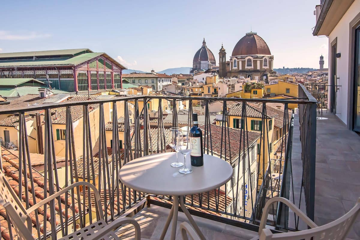 A balcony with a table, two wine glasses, and a bottle of wine.