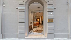 Una entrada arqueada a un hotel con una recepción, un mostrador de registro y un cartel con el número 10.