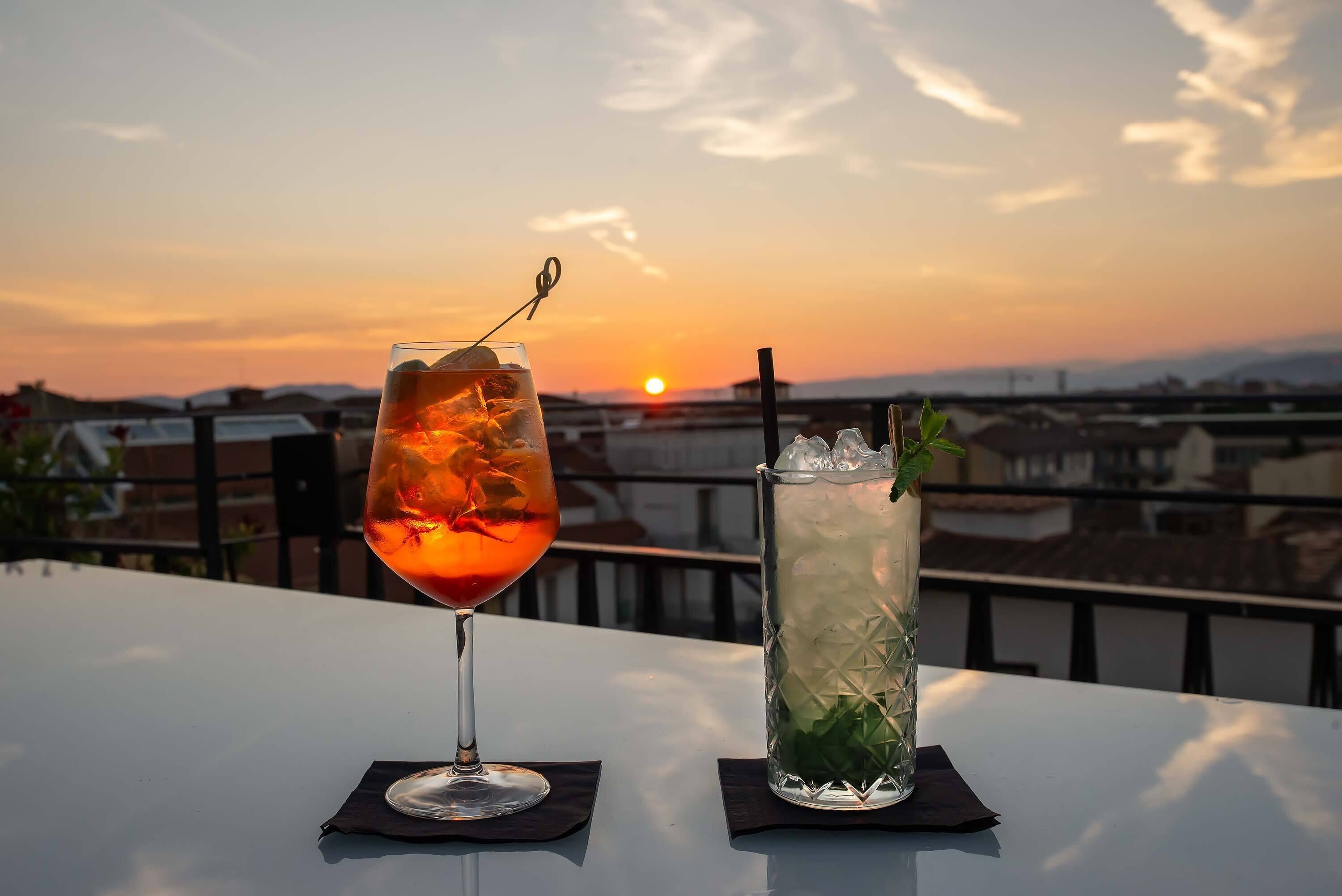Two drinks on a table with a sunset view.