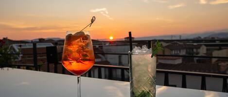 Two drinks on a table with a sunset view.
