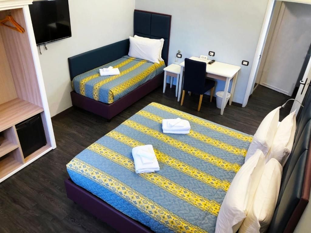 Una habitación de hotel con dos camas, un escritorio y una televisión.