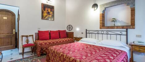 A room with two beds, a wooden door, a chair, a nightstand, and a painting on the wall.