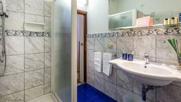 Ein Badezimmer mit Dusche, Waschbecken und Spiegel.