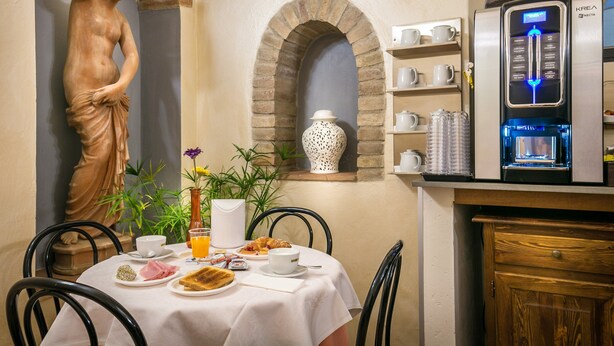 Un desayuno con una estatua, un dispensador de agua y un florero en la pared.