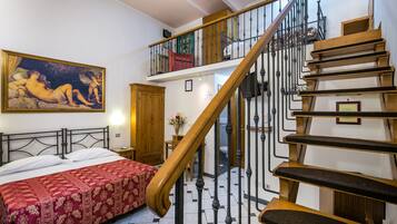 A bedroom with a bed, a staircase, and a painting on the wall.