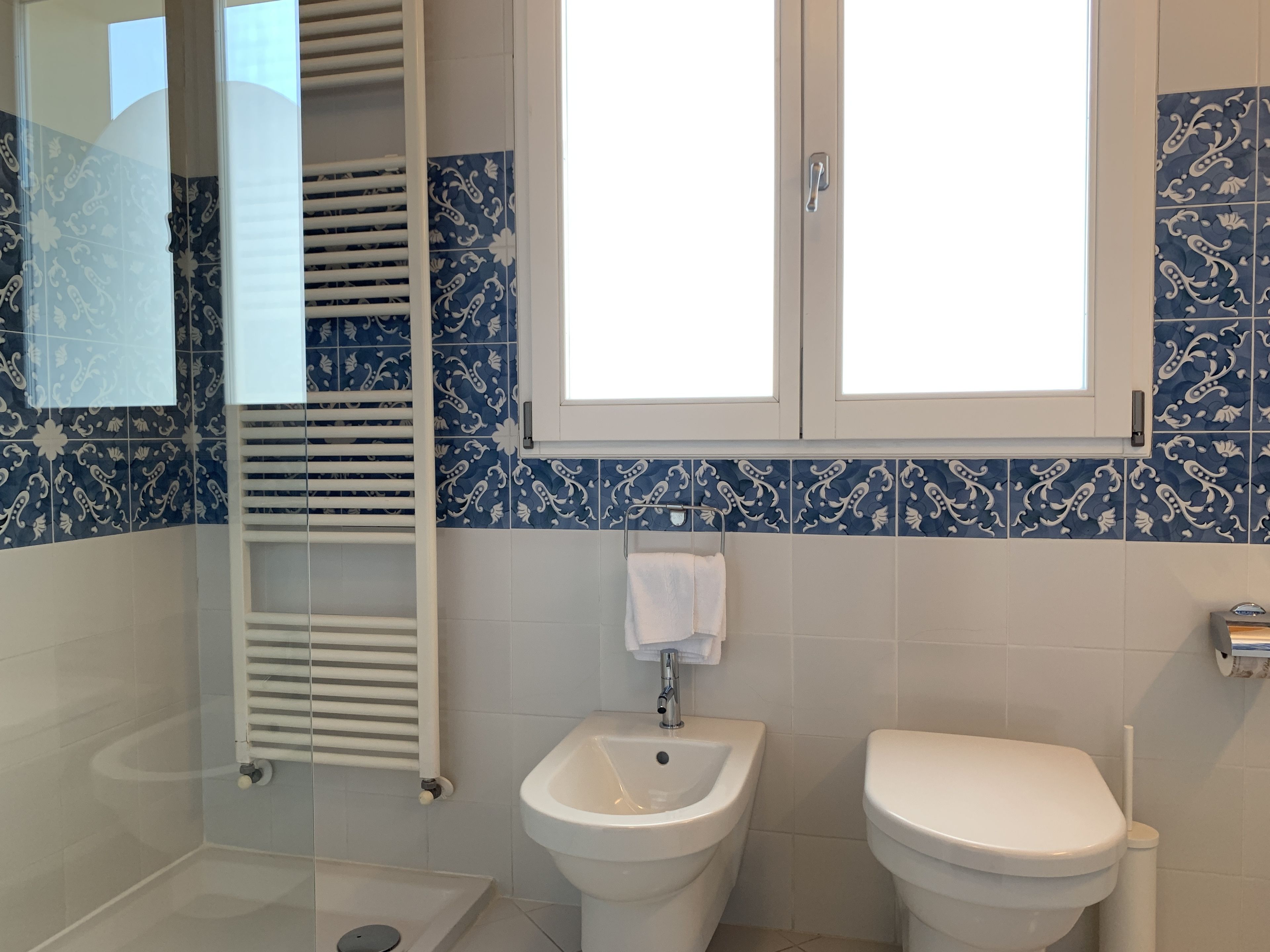 A bathroom with a white sink, a toilet, and a towel hanging on the wall.