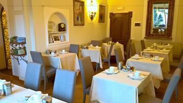 A dining area with multiple tables set for service, chairs, and a clock on the wall.
