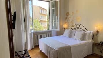 A bedroom with a bed, a window, a radiator, and a wall-mounted lamp.