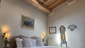 Un dormitorio con cama, techo de madera, un cuadro, espejo y apliques de pared.