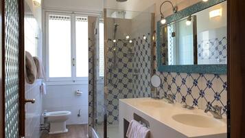 A bathroom with a shower, toilet, and dual sinks.