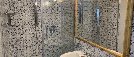 A bathroom with a white sink, a mirror, and a shower with a glass door.