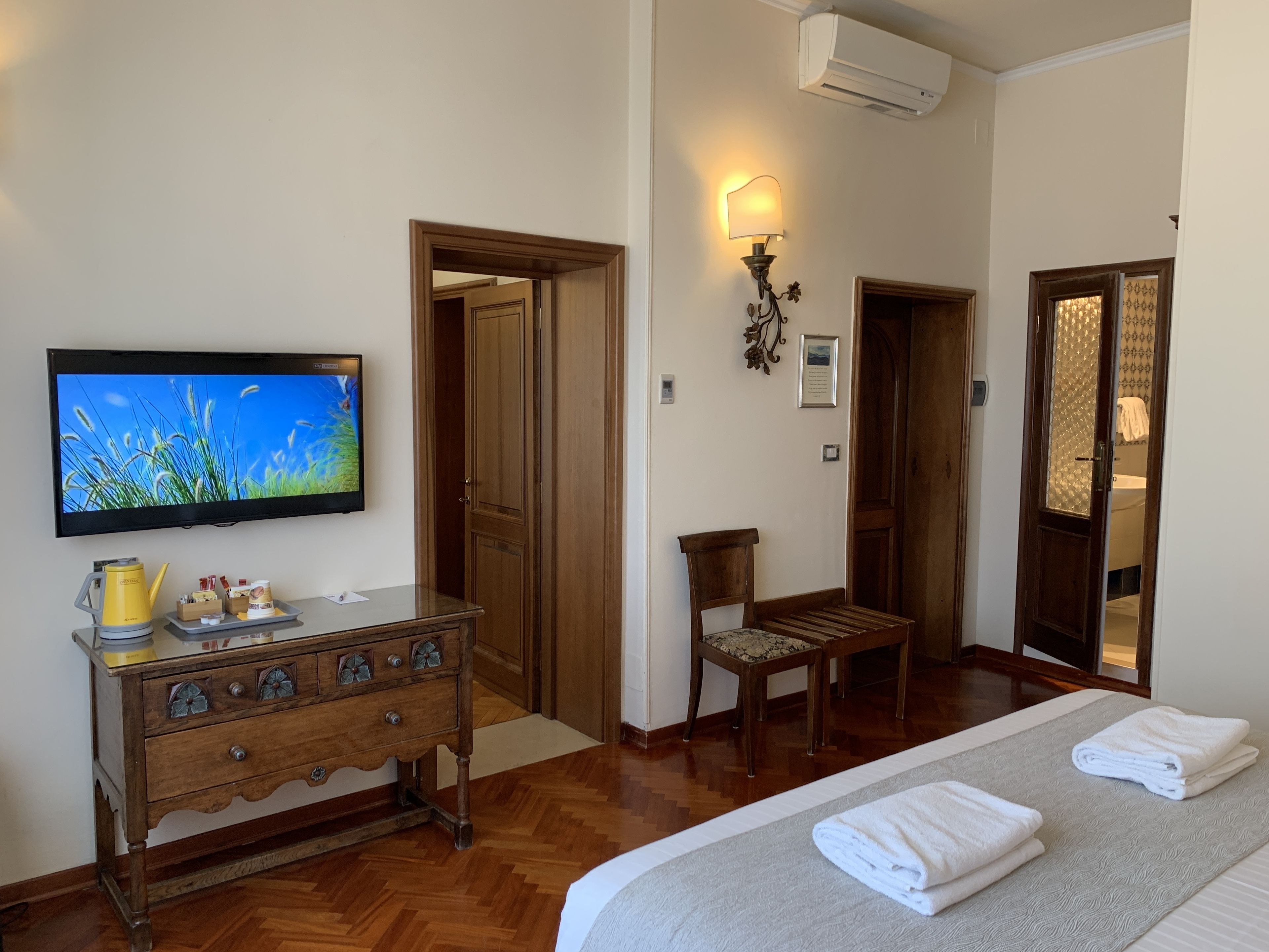 Ein Hotelzimmer mit einem Bett, einem Holzschrank, einem Fernseher und einem Sessel.