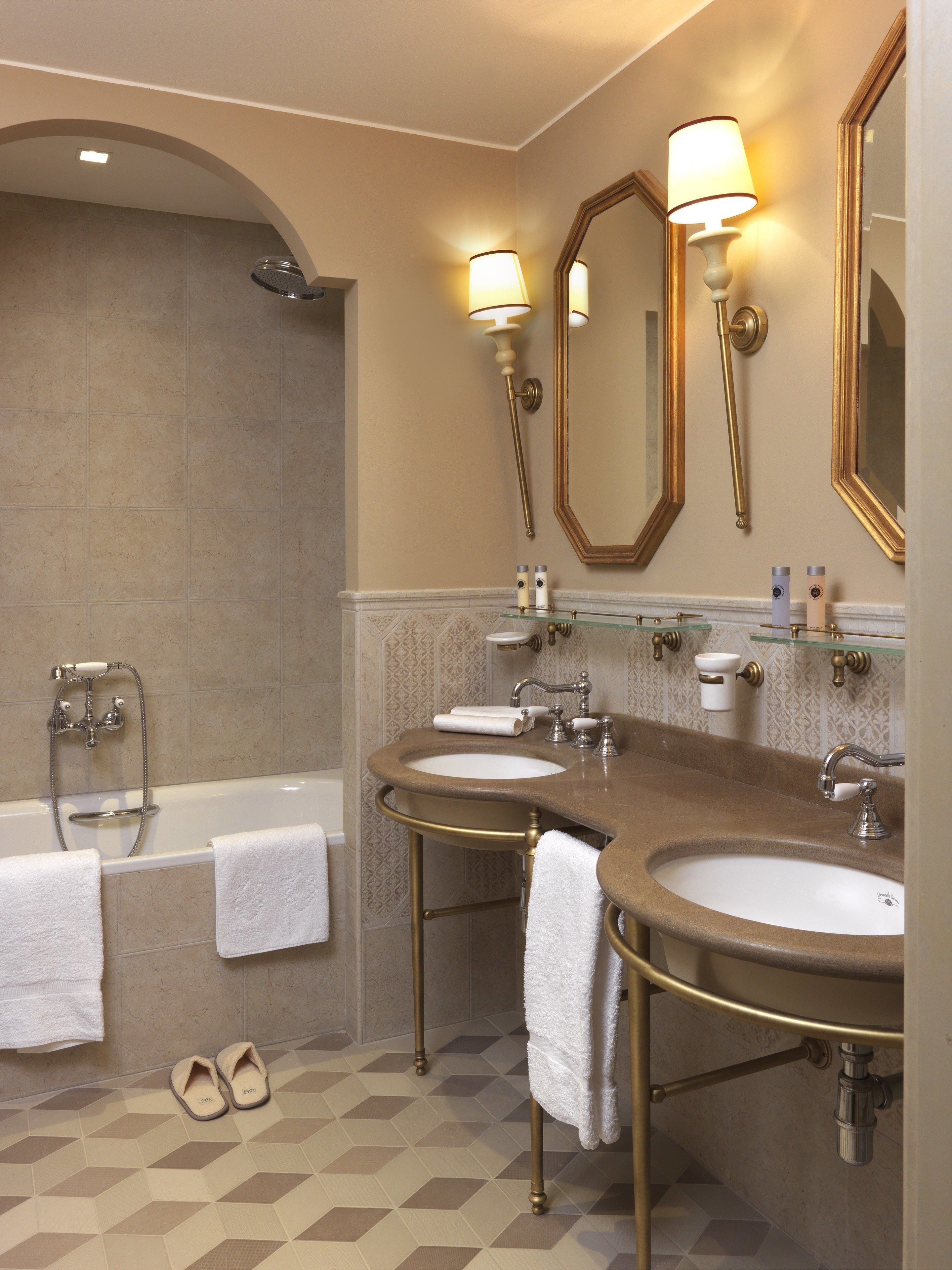 A bathroom with two sinks, a bathtub, and a shower. There are towels and slippers on the floor.