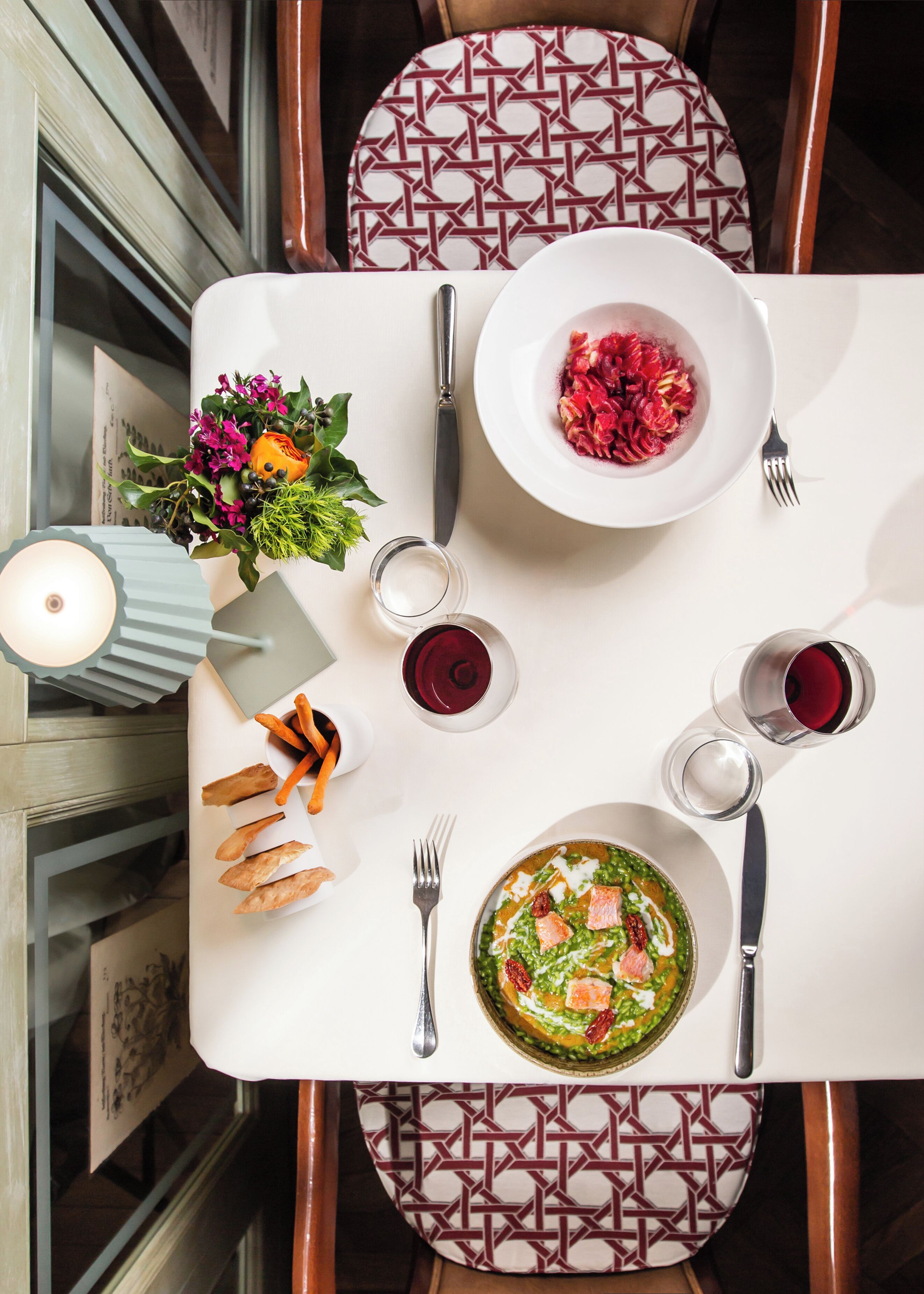 A dining table set with plates, cutlery, glasses, and a candle.