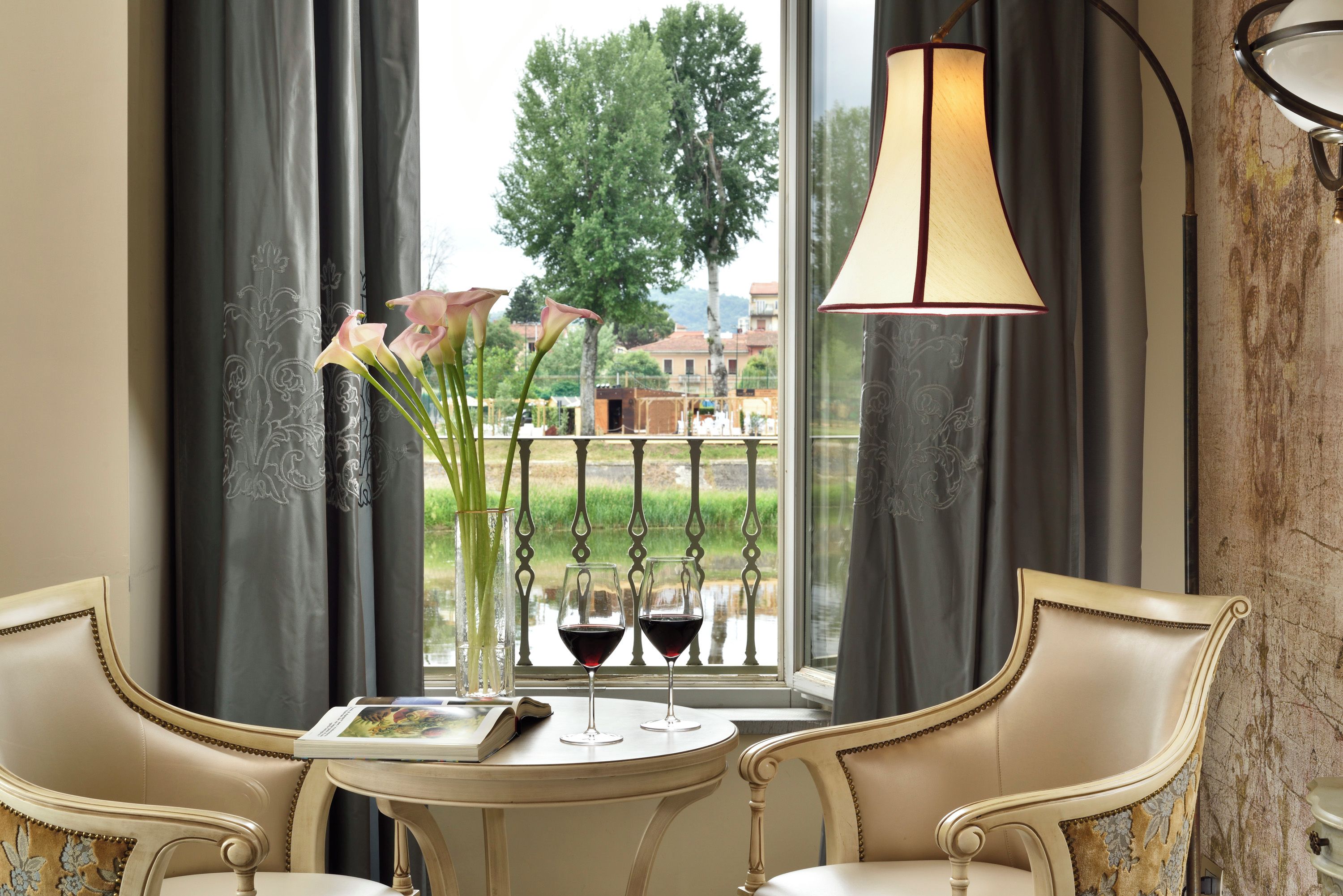 Une pièce comprenant une table, deux chaises, un vase avec des fleurs et deux verres à vin.