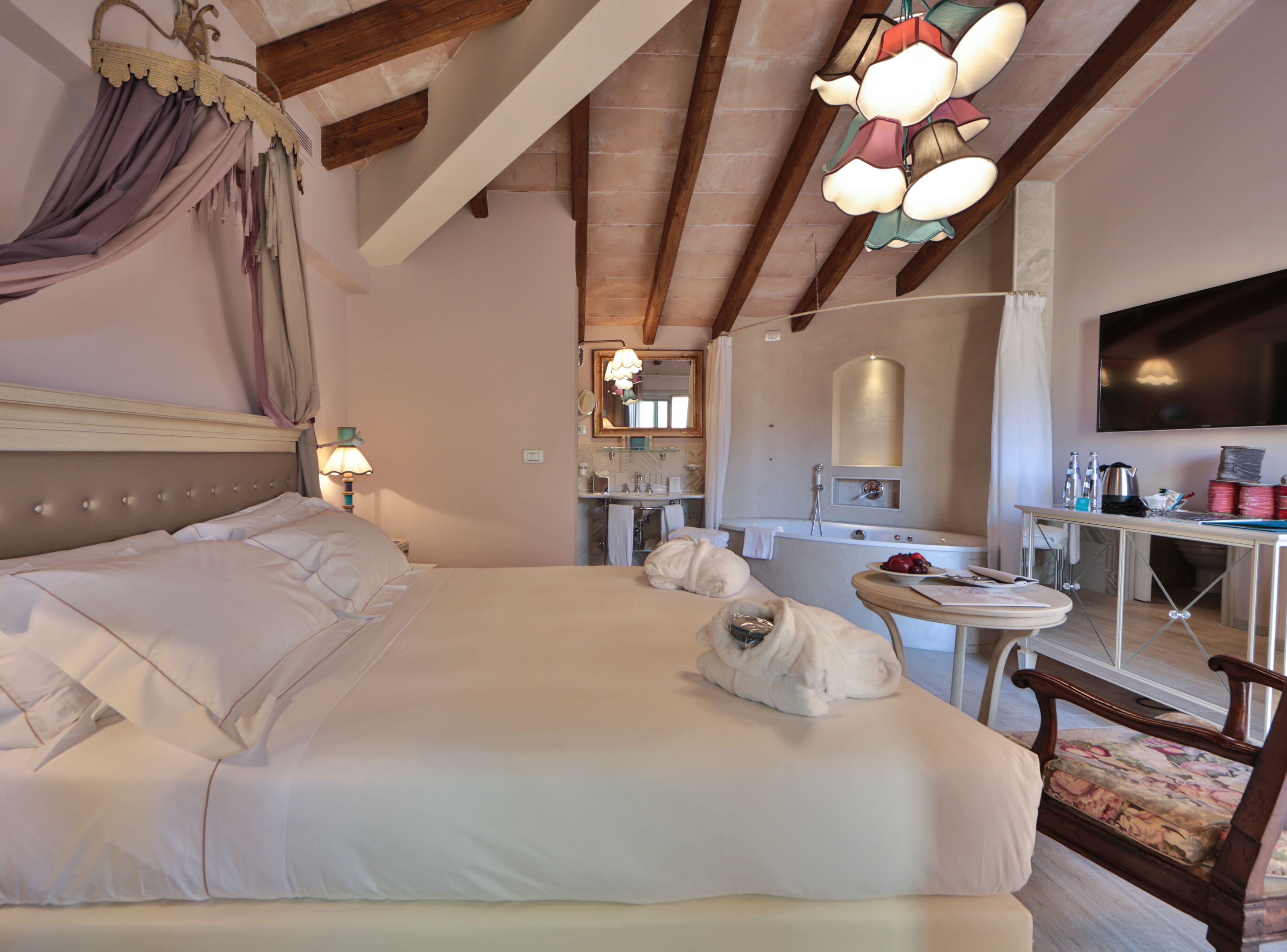 Une chambre à coucher avec un grand lit, un bureau, une chaise, une télévision et, au fond, une salle de bain.