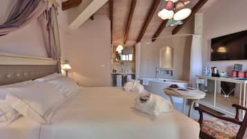 Une chambre à coucher avec un grand lit, un bureau, une chaise, une télévision et, au fond, une salle de bain.