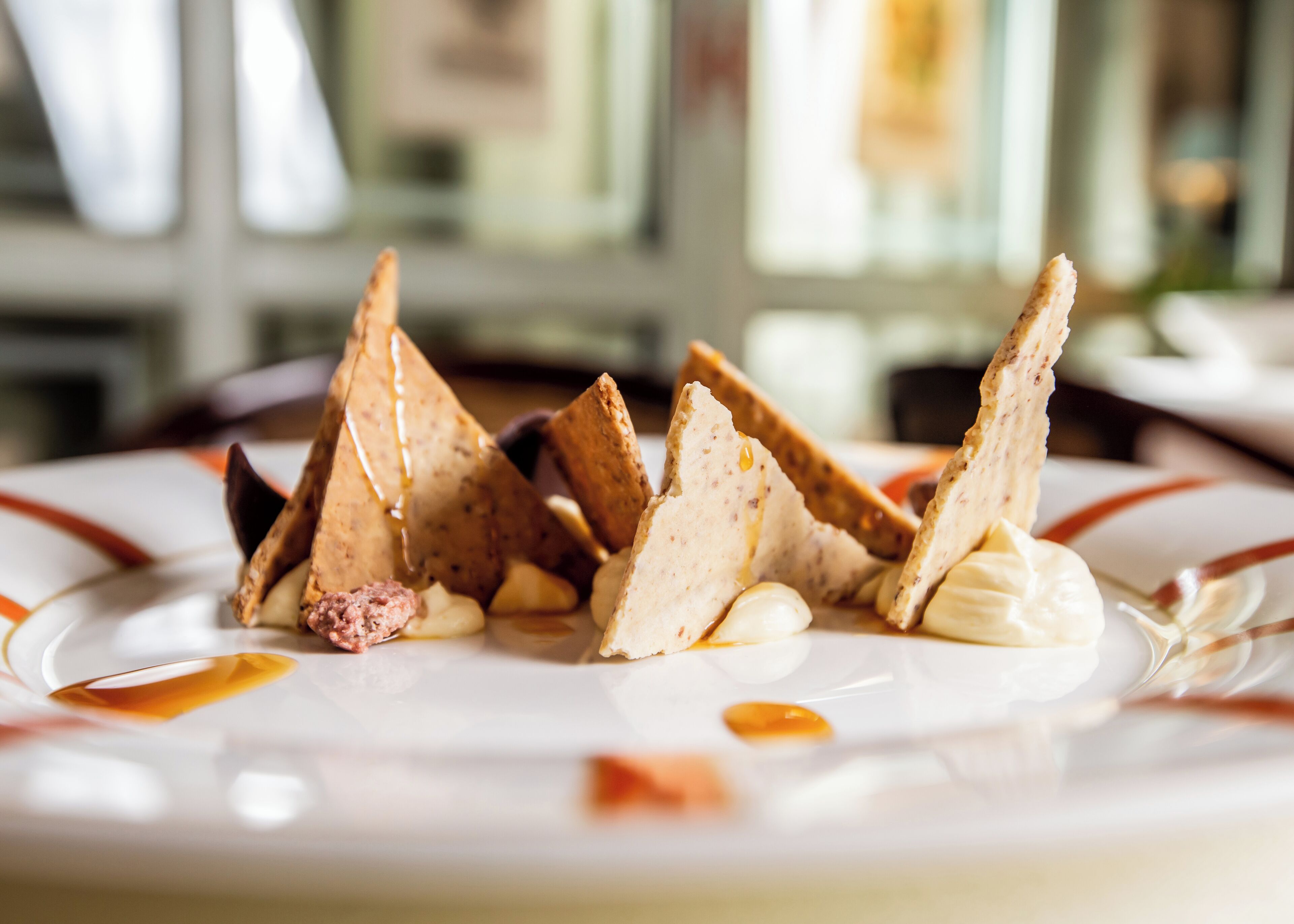 A plate of food with triangular crackers and a dollop of cream.
