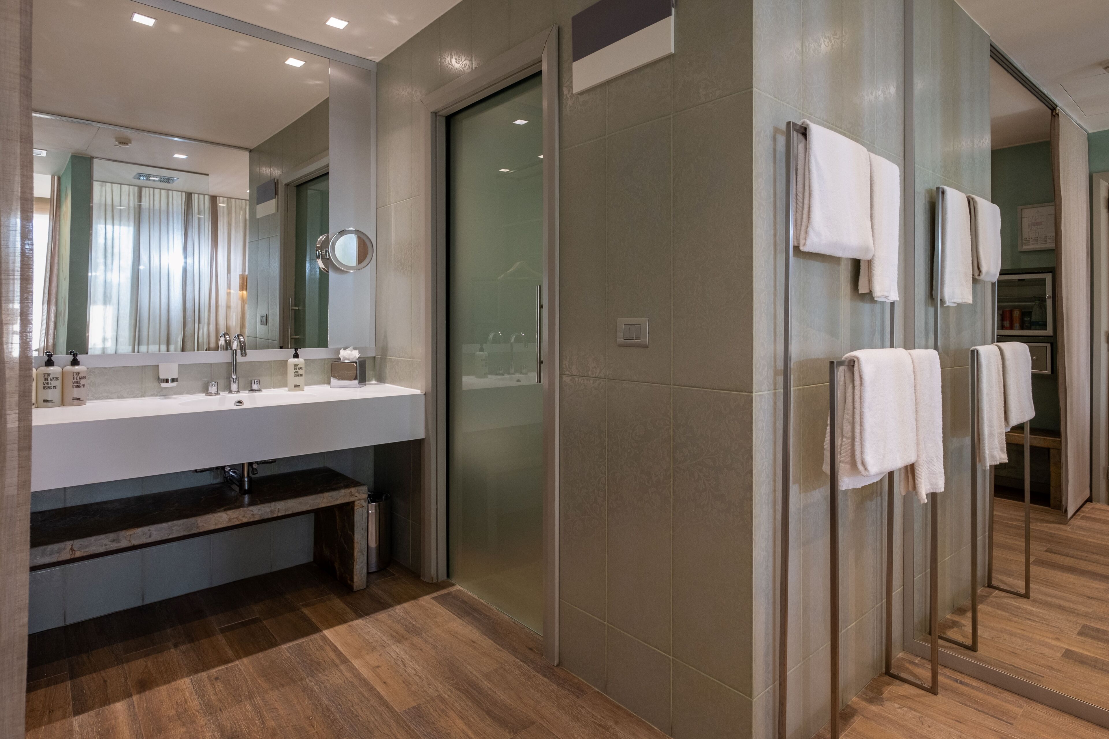 A modern bathroom with a glass shower enclosure, a vanity with a mirror, and a towel rack.