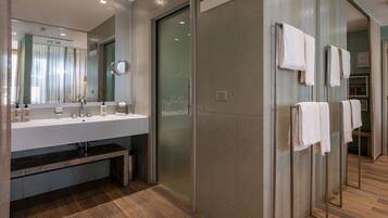 Un baño moderno con cabina de ducha de vidrio, tocador con espejo y perchero.