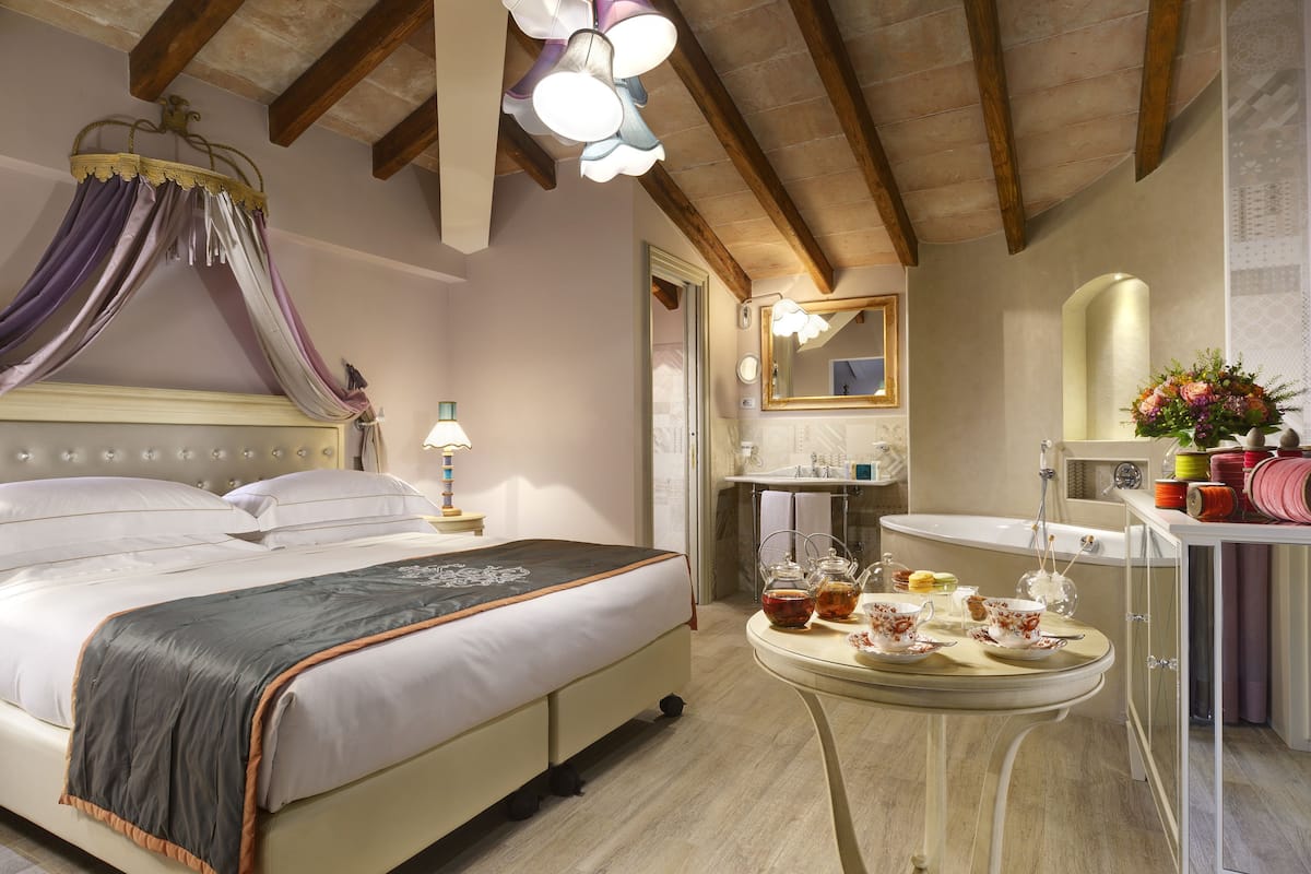 A bedroom with a bed, bedside table, lamp, and a vanity with a mirror.